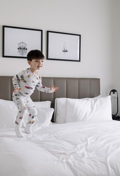 a kid jumping on the bed in steveston village at steveston waterfront hotel