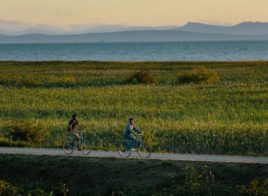 Two people ride bicycles along the dike in Richmond in front of the Pacific Ocean
